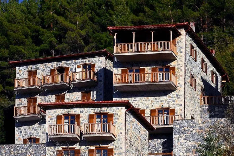 Το ψηλό πέτρινο κτίριο με τα ξύλινα μπαλκόνια μέσα στο πευκοδάσος